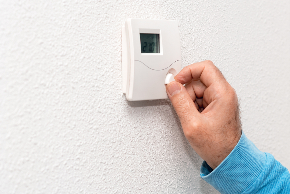 man,hand,adjusting,thermostat,at,home.,celsius,temperature,scale.